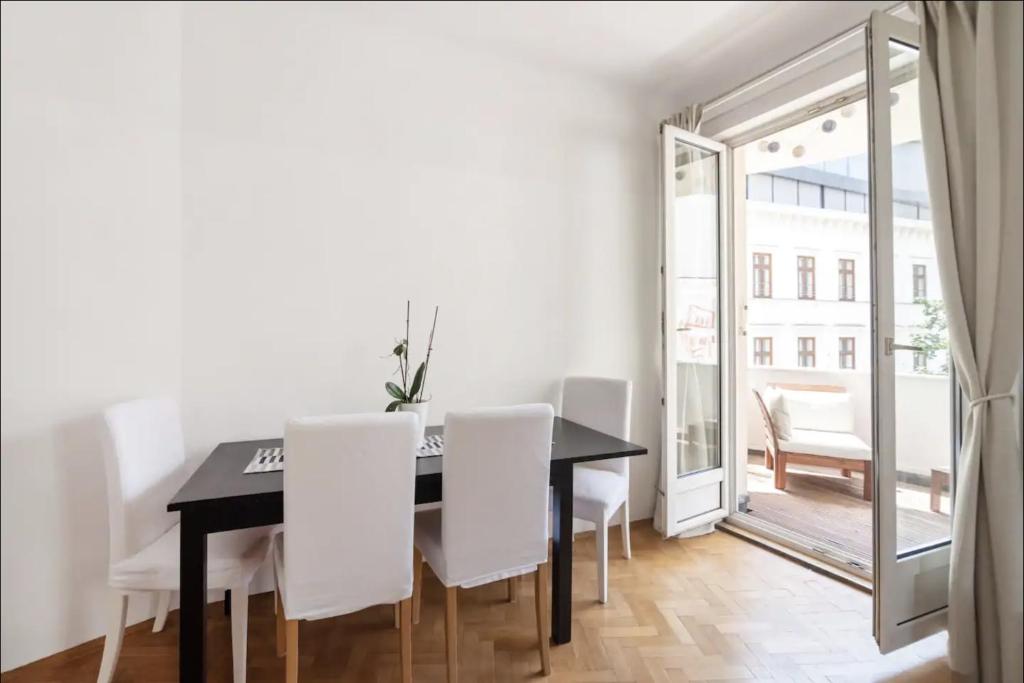 een eetkamer met een zwarte tafel en witte stoelen bij Balcony Oasis Operastreet in Wenen