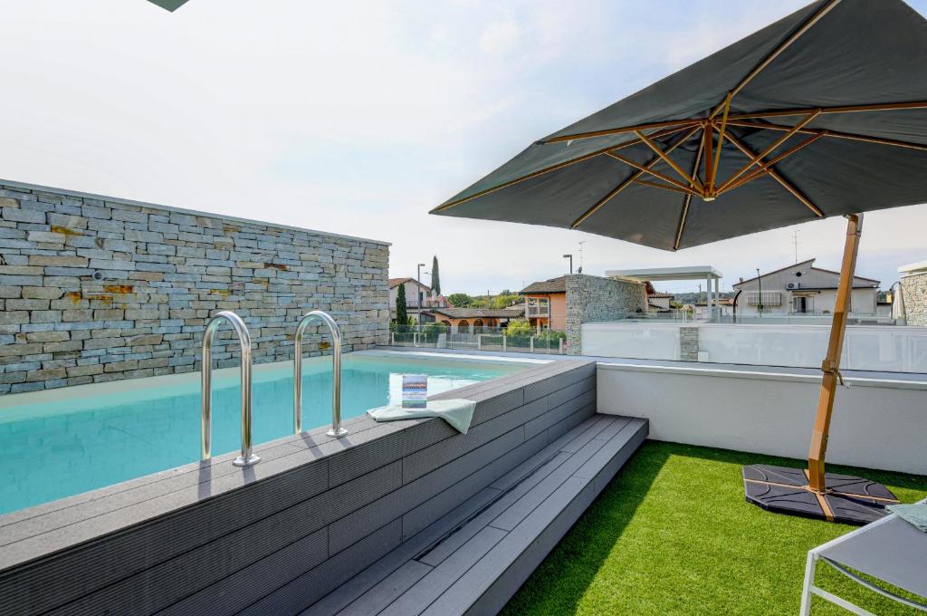 un patio con sombrilla y piscina en Villette Dolci Luxury Homes, en Peschiera del Garda