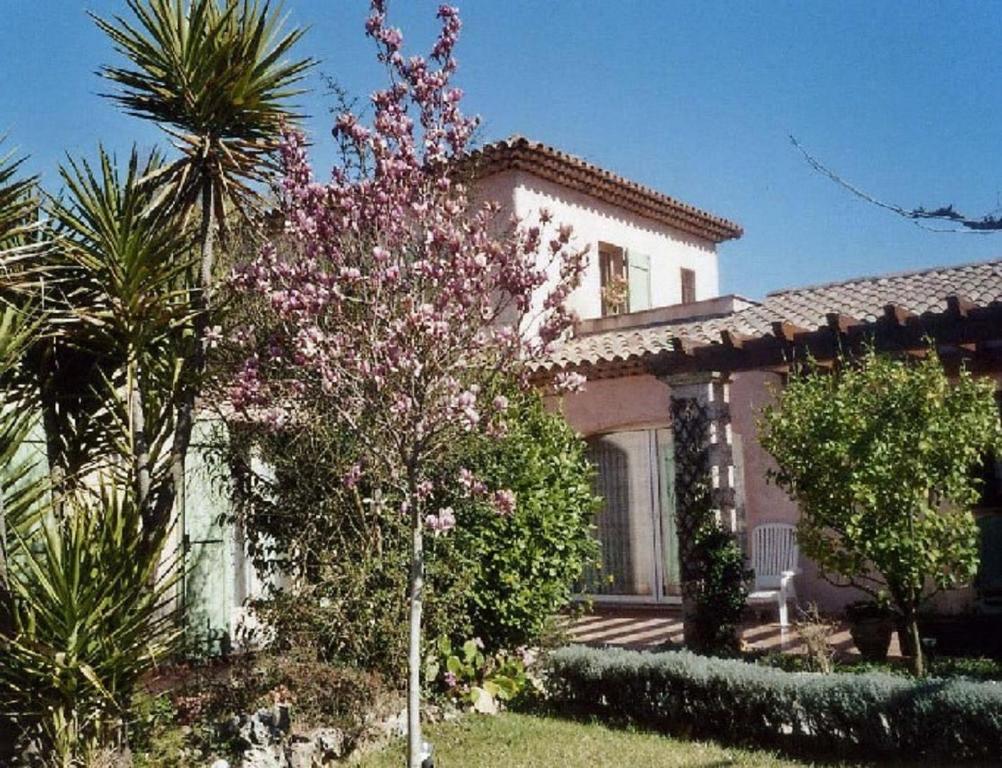 una casa con un árbol floreciente delante de ella en Dolce-Nido, en Mougins