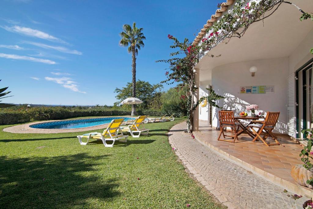 un patio trasero con mesa, sillas y piscina en Casa do Barrocal, en Almancil