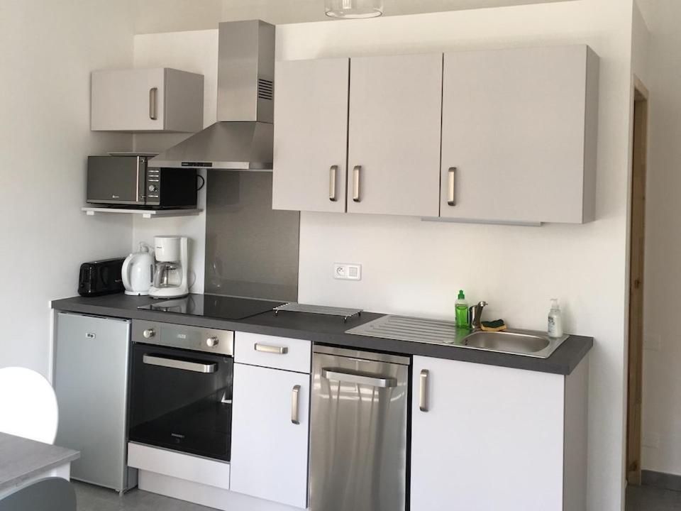 a kitchen with white cabinets and a black appliance at Ernella in Bastia