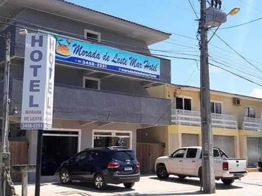 two cars parked in front of a building with a sign at Hotel Morada de Leste in Pontal do Paraná
