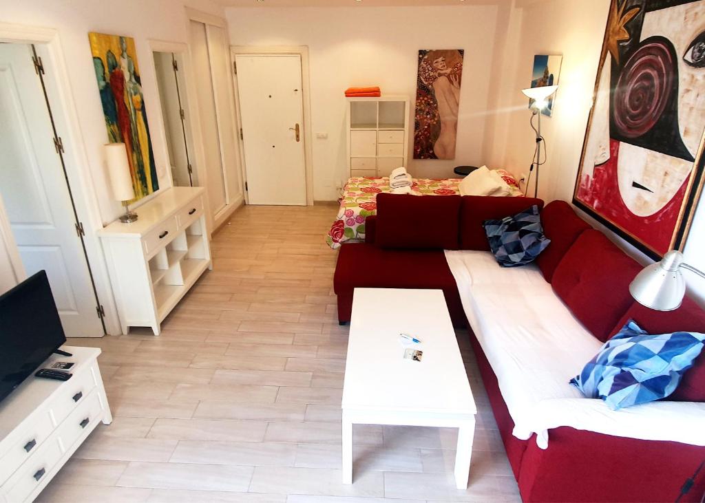 - un salon avec un canapé rouge et un lit dans l'établissement Skol 219. Studio Apartment Skol Marbella with Sea Views, à Marbella