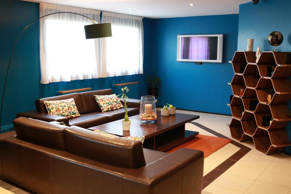 a living room with a brown couch and blue walls at Orly Superior Hotel in Athis-Mons