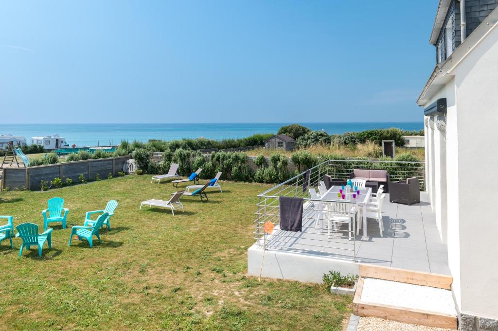 a patio with chairs and tables and the ocean in the background at Maison Face à la Mer - Penhors in Pouldreuzic