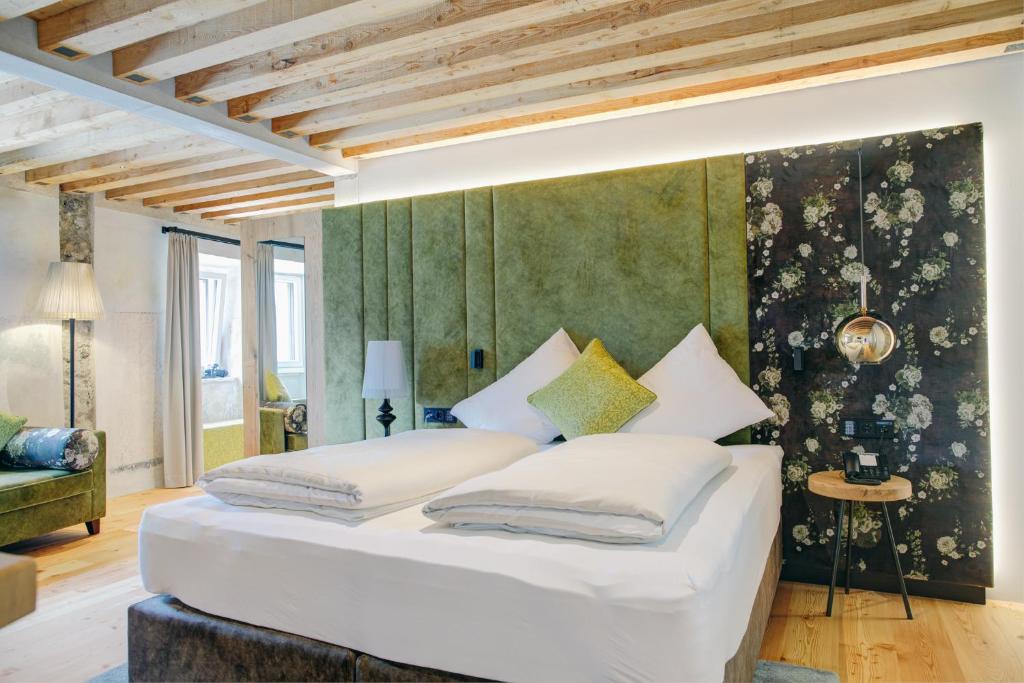 a large white bed in a room with a green wall at Boutique Hotel im Auracher Löchl in Kufstein