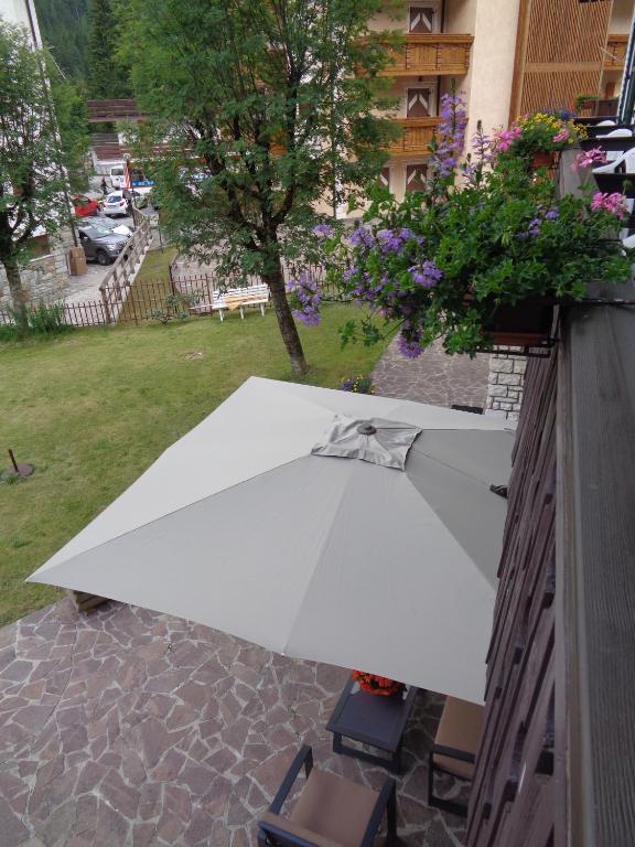 a white umbrella sitting on a table in a yard at Hotel Garni Suisse in San Martino di Castrozza