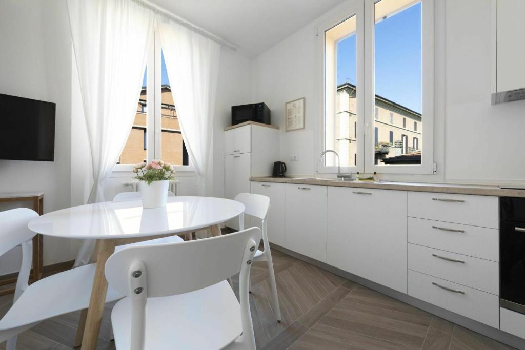 una cucina bianca con tavolo e sedie bianche di Palazzo Pedretti Halldis Apartments a Bologna