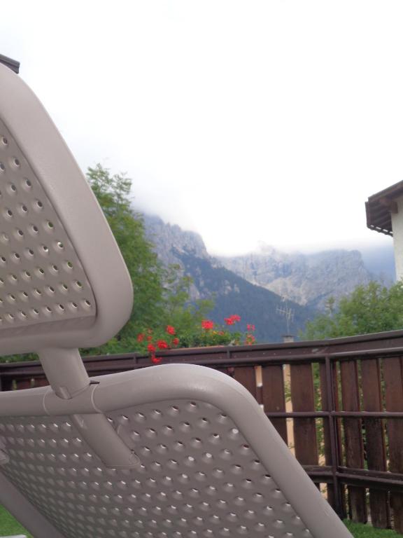 a white bench sitting on a balcony with mountains in the background at Hotel Garni Suisse in San Martino di Castrozza