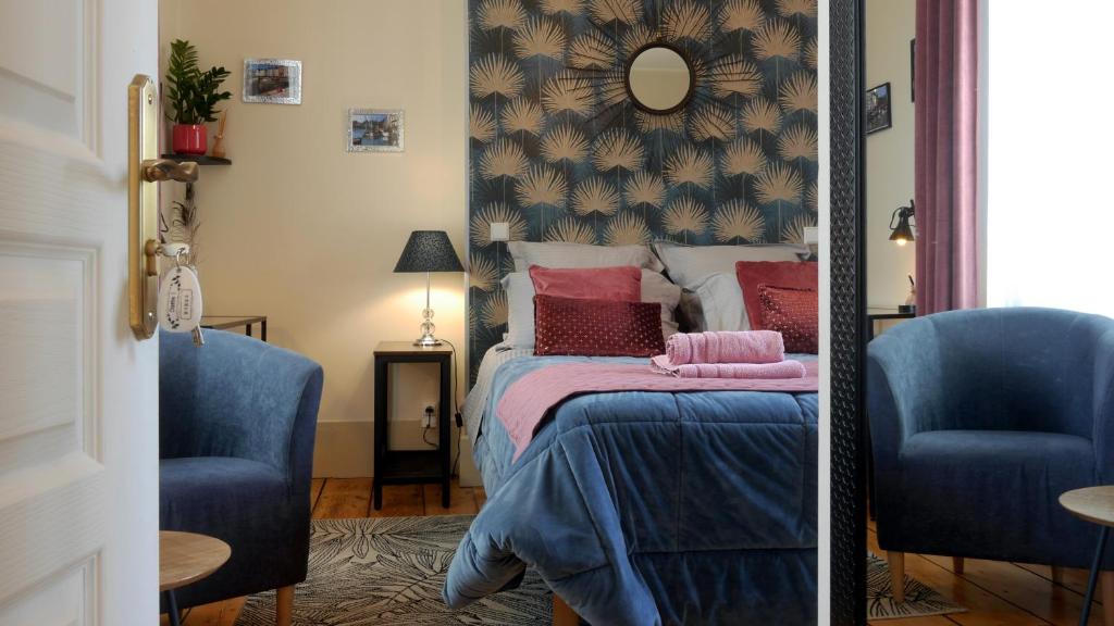a bedroom with a bed and two blue chairs at Entre Terre et Estuaire & Spa in La Rivière Saint Sauveur