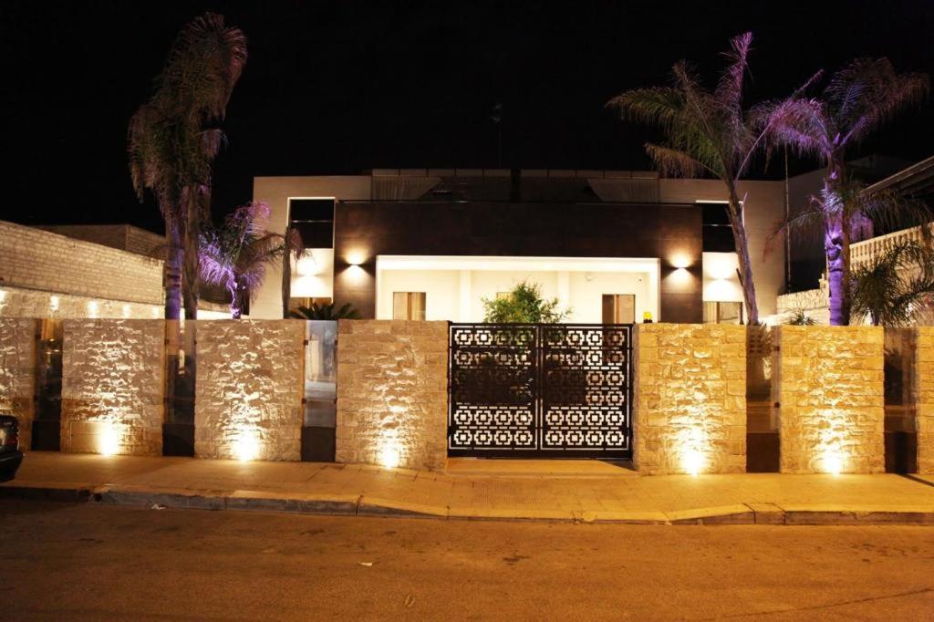 B&B Villa Grace في باري: سور مع أضواء أمام منزل في الليل