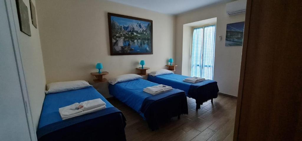 três camas num quarto com lençóis azuis em Il Tronchetto em Monte Libretti