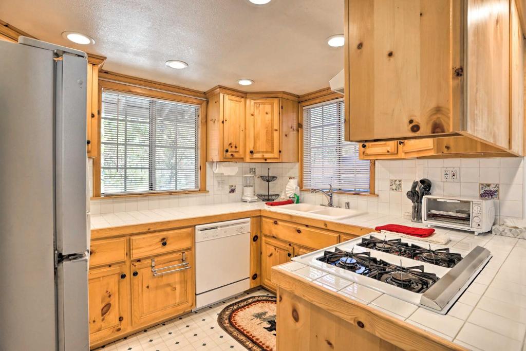 uma cozinha com armários de madeira e um forno com placa de fogão em Cozy Cottage with Spacious Yard about 4 Mi to Ski! em Big Bear City
