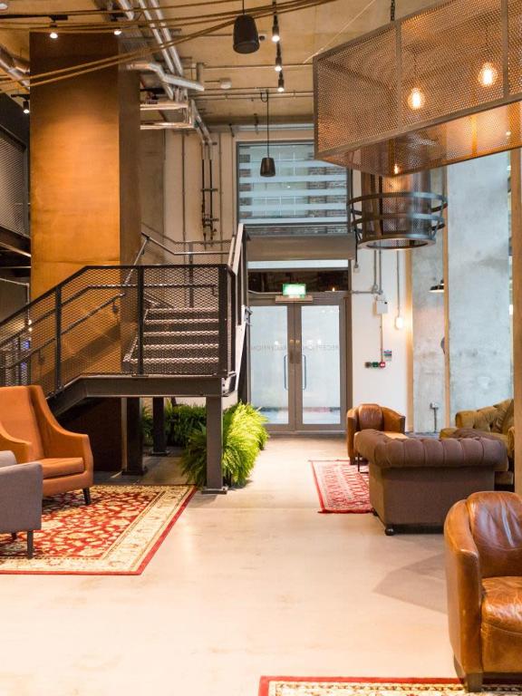 a lobby with a staircase and couches in a building at Chapter Aldgate London in London