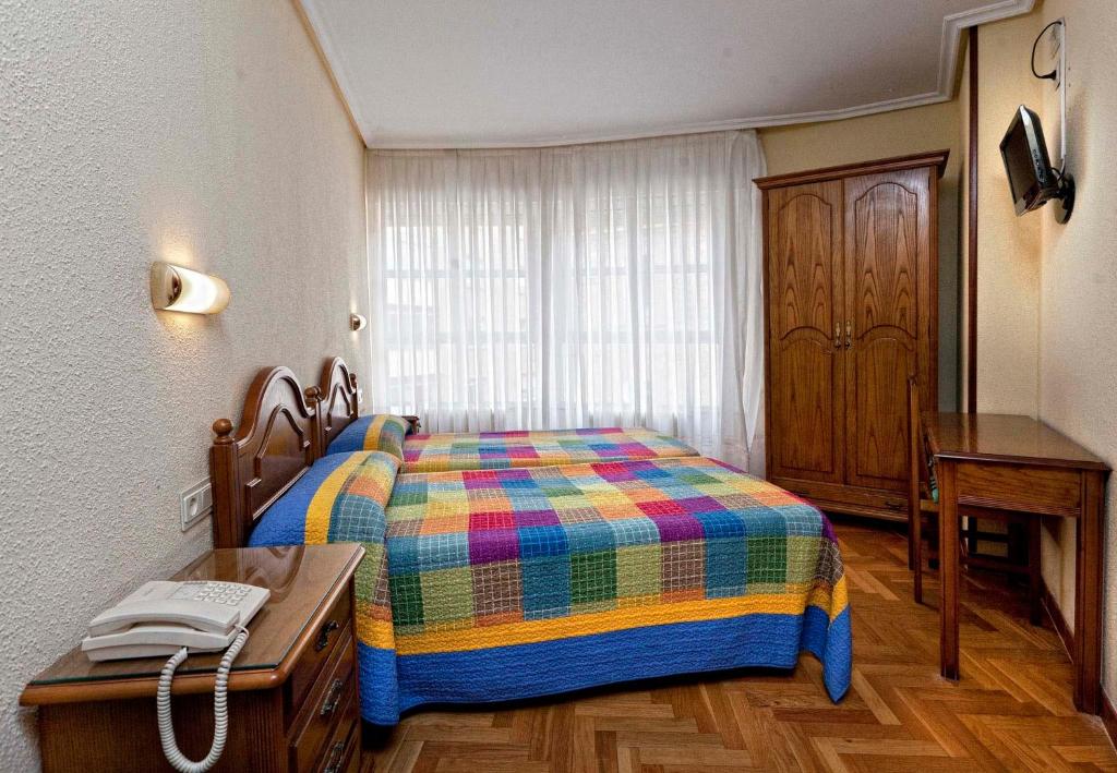 1 dormitorio con 1 cama y 1 mesa con teléfono en Hostal Hispano, en Nájera