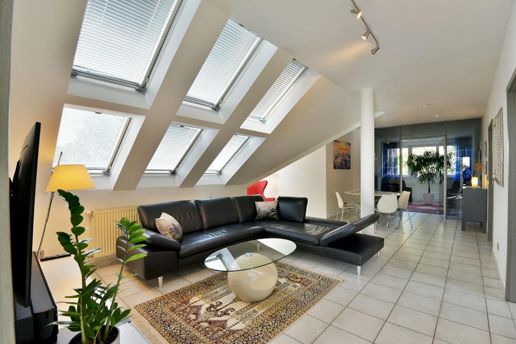 sala de estar con sofá negro y algunas ventanas en Studioappartment SAALEBLICK, en Rudolstadt
