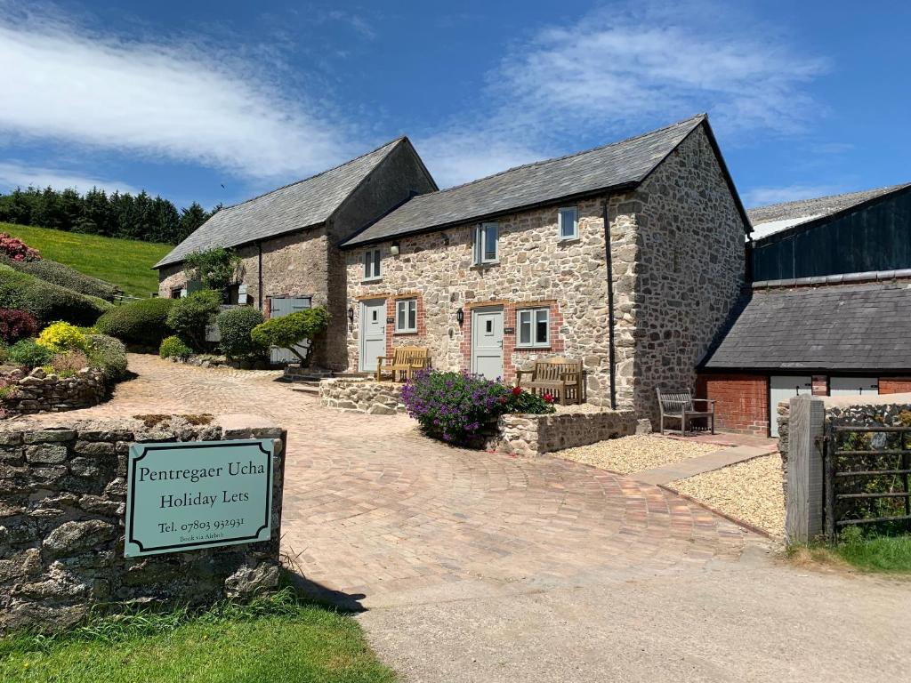 a stone house with a sign in front of it at The Nook at Pentregaer Ucha, with tennis court & lake. in Oswestry