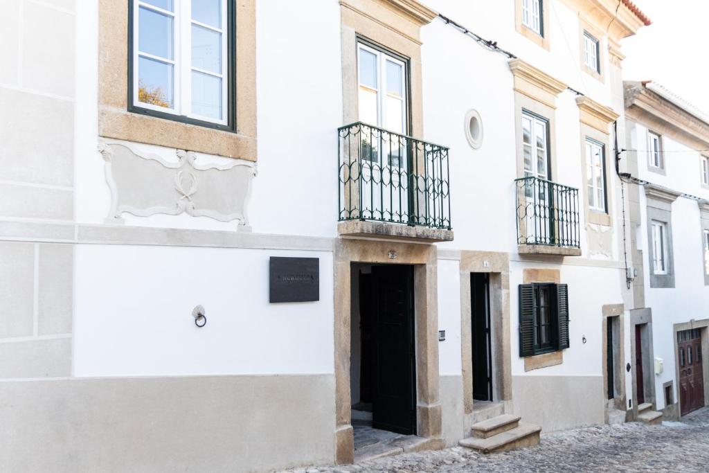 biały budynek z czarnymi drzwiami i balkonem w obiekcie A BURGUESA - GUESTHOUSE w mieście Castelo de Vide