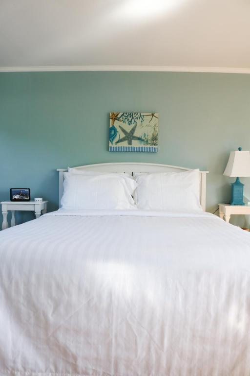 a bedroom with a white bed with a blue wall at The Escape Inn in South Yarmouth