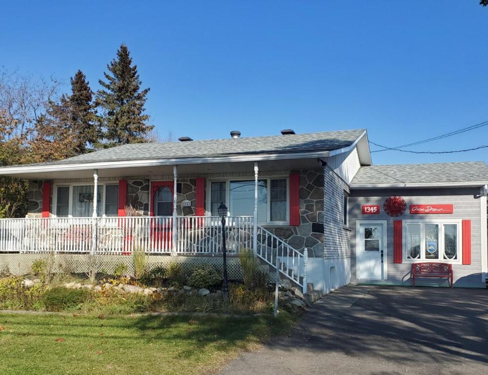 a red and white house with a porch at Atelier Galerie Anne Drouin Peinture & Pension in Sainte-Julie