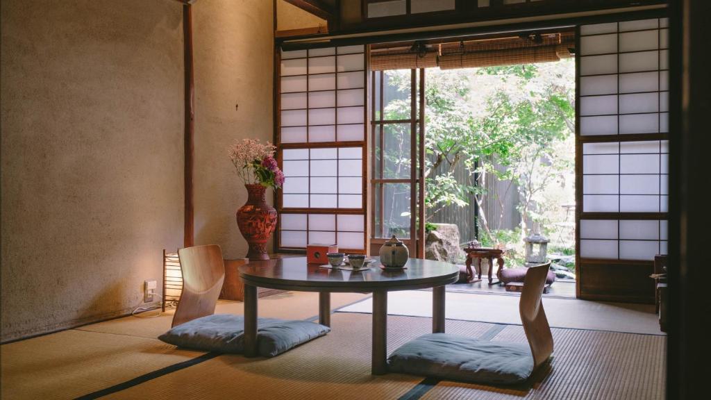 een kamer met een tafel en stoelen en een raam bij お宿梅夜Guesthouse Umeya in Kyoto