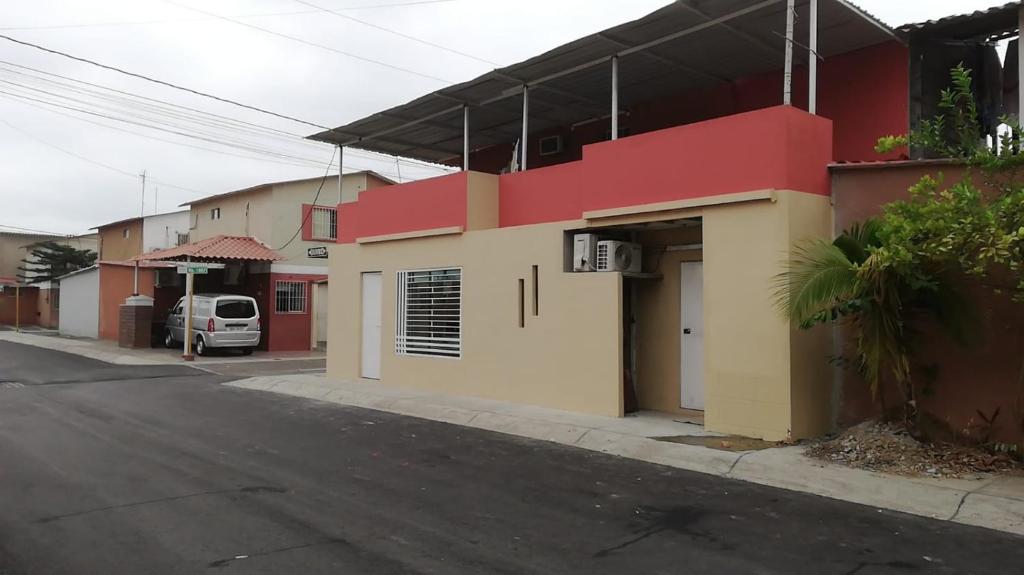 una calle con un edificio rojo y amarillo en una calle en EN EL EXTRANJERO COMO EN CASA, en Guayaquil