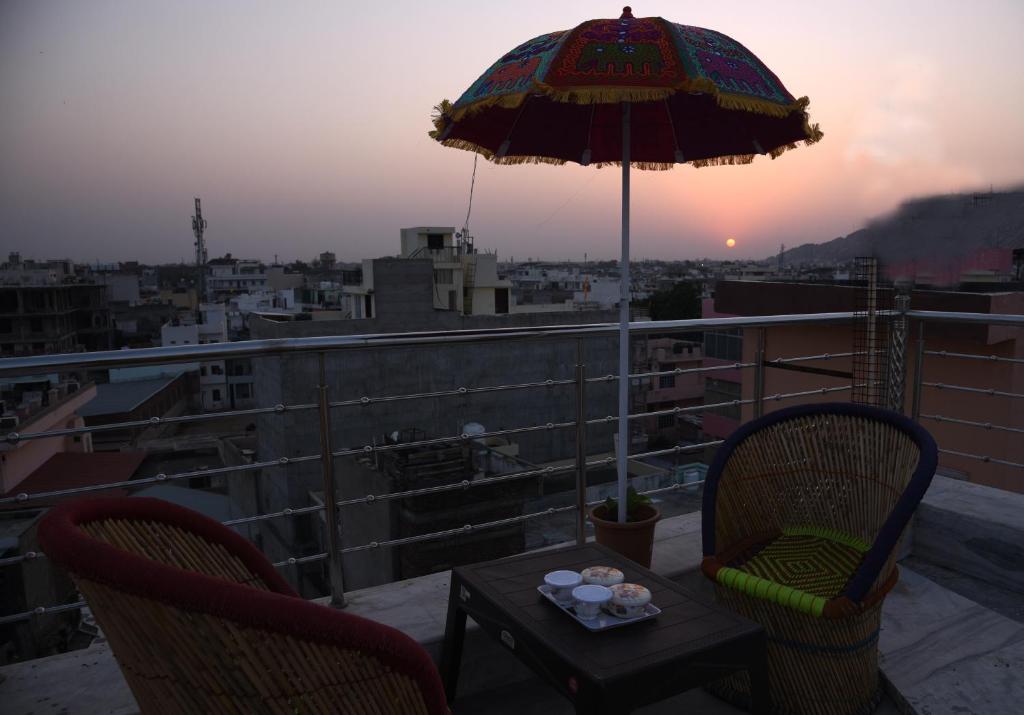 a table and chairs with an umbrella on a balcony at Laxmi Residence in Jaipur