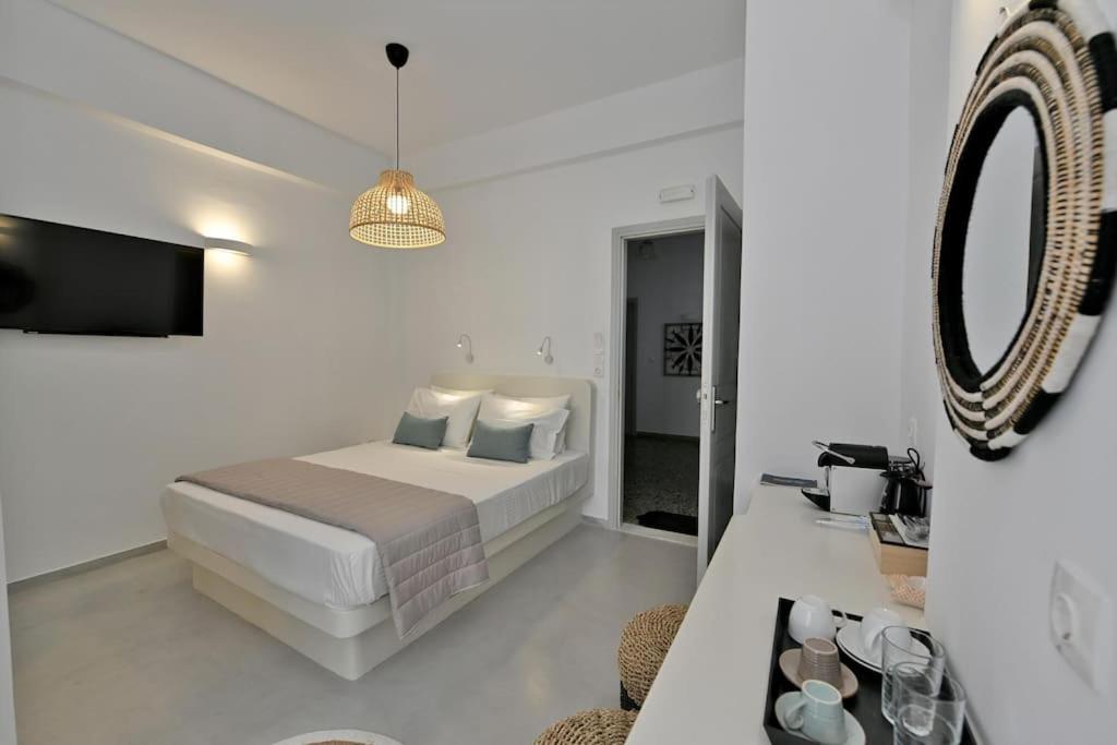 a white bedroom with a bed and a mirror at Kleri's apartments 2 in Tinos Town