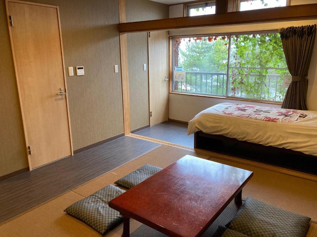 a room with a bed and a table and a window at Koya TRIBE - Vacation STAY 83064v in Oishi