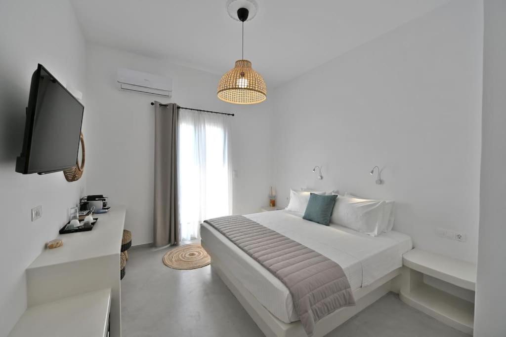 a white bedroom with a bed and a television at Kleri's apartments 5 in Tinos Town