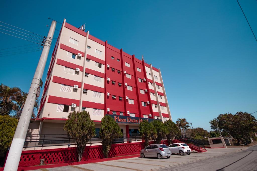 un edificio rojo con coches estacionados frente a él en Plaza Dutra Hotel, en Caçapava