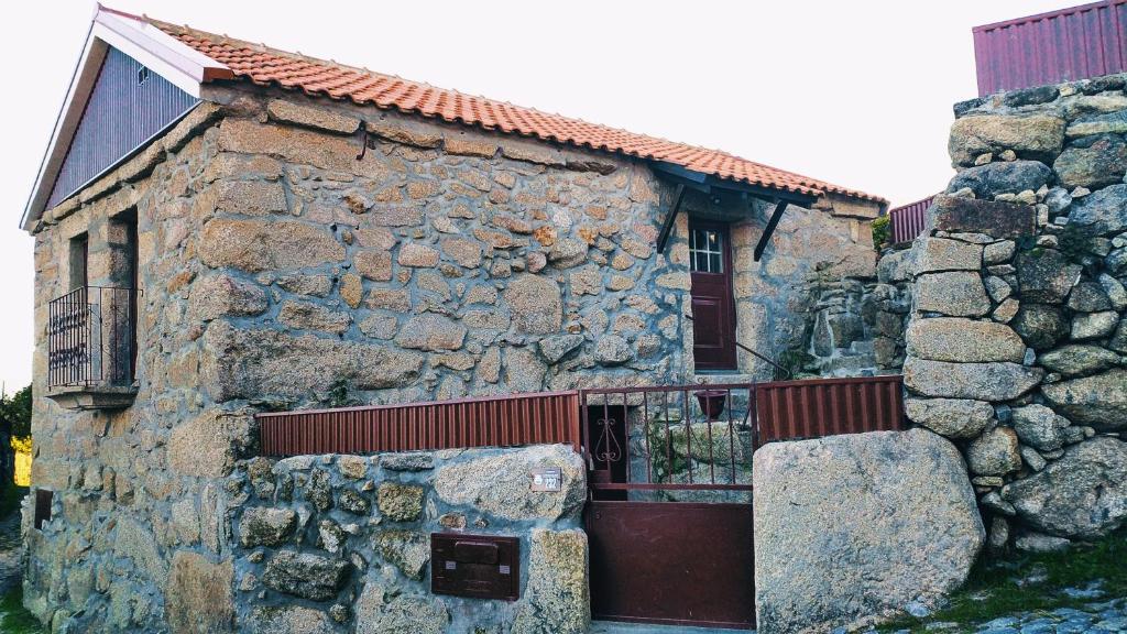 ein altes Steingebäude mit einem Tor und einer Steinmauer in der Unterkunft Casa João Rodas in Soajo