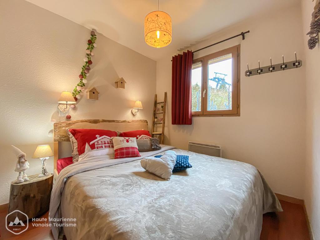 a bedroom with a large bed with red pillows at VALFREJUS - Appartement "L'Erable" Les Chalets de Florence 2 - Chaleureux et fonctionnel - plein centre à côté des télécabines - 4 à 7 pers in Valfréjus