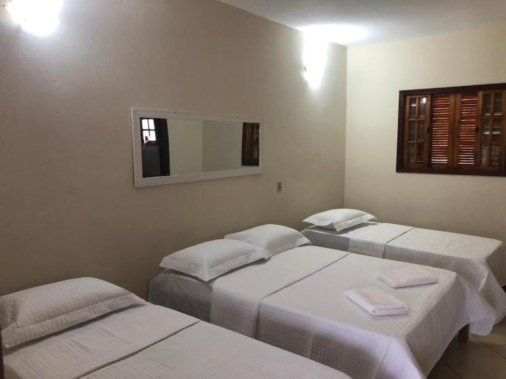 three beds in a room with a mirror at Pousada Esperança in Boa Esperança