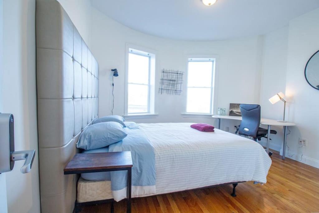 a white bedroom with a large bed and a desk at 3BD 1,5BTH Spacious Apt in Mission Hill in Boston