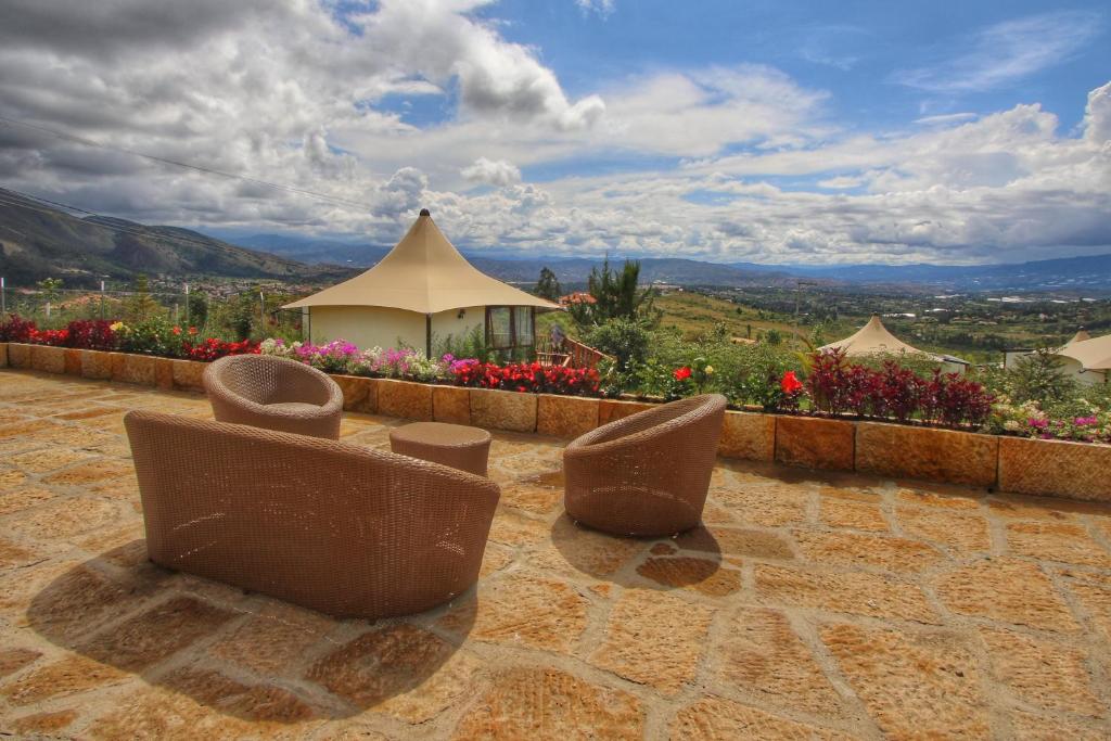 - un ensemble de chaises assises sur une terrasse fleurie dans l'établissement GENKI LUXURY GLAMPING, à Villa de Leyva