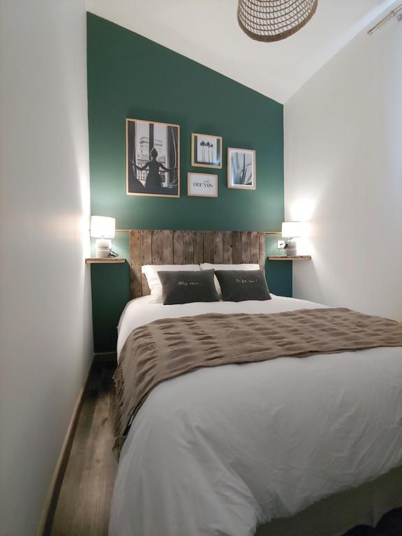 - une chambre avec un grand lit et un mur vert dans l'établissement LES GRENOUILLES, à Amiens