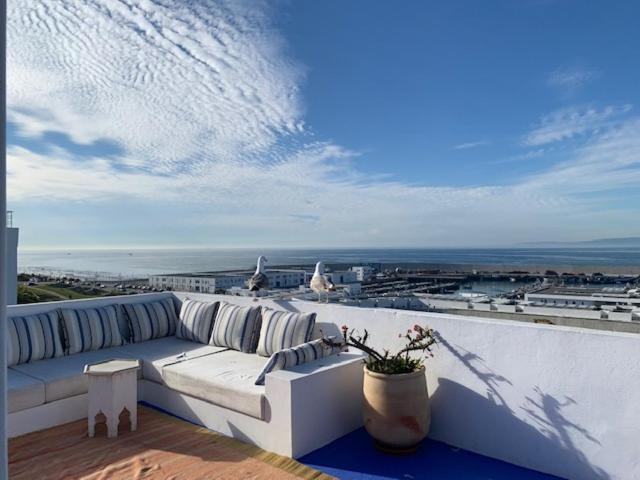 Tanger *Maison avec terrasse et vue sur la mer * في طنجة: أريكة بيضاء تجلس على شرفة