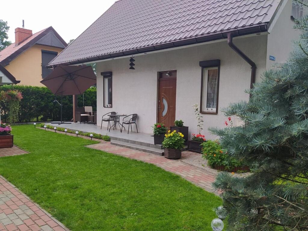 a white house with a table and chairs and an umbrella at Holiday house with swimming pool in Morzyczyn in Morzyczyn
