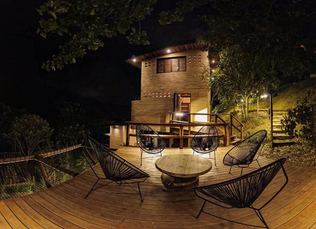 una terraza de madera con sillas, una mesa y una casa en Palagua Lodge en San Rafael