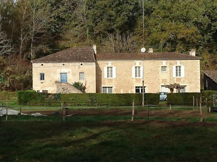uma grande casa de tijolos com uma cerca em frente em Location meublée au milieu d'un écrin de verdure Aux vieux fours em Noaillac