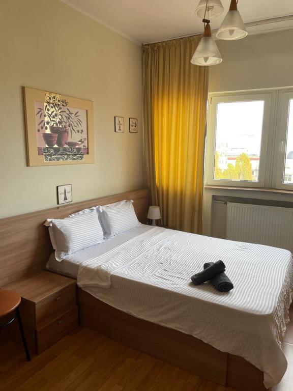 1 dormitorio con 1 cama grande con sábanas blancas y ventana en Downtown Studio, en Bucarest