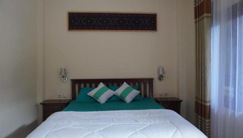 Schlafzimmer mit einem Bett mit grünen und weißen Kissen in der Unterkunft JOGLO Greenhouse in Ngemplak