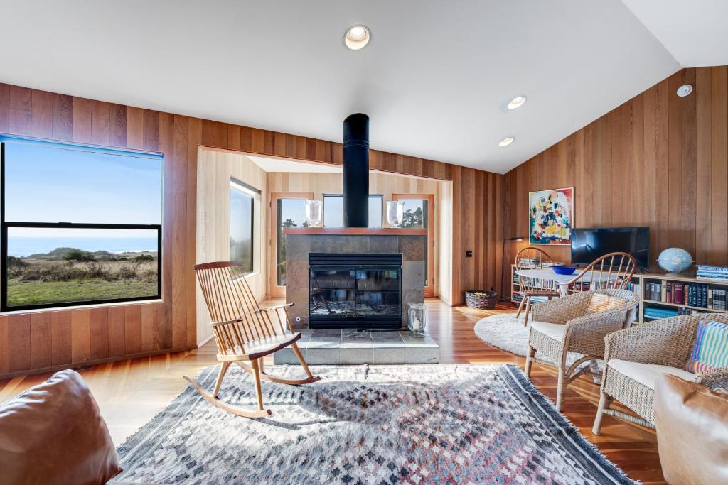 a living room with a fireplace and wooden walls at Cypress Meadow in Sea Ranch