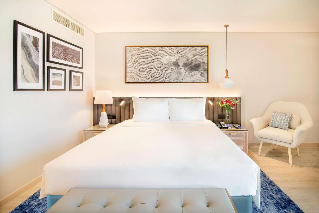 a bedroom with a large white bed and a chair at Radisson Blu Hotel & Resort, Abu Dhabi Corniche in Abu Dhabi