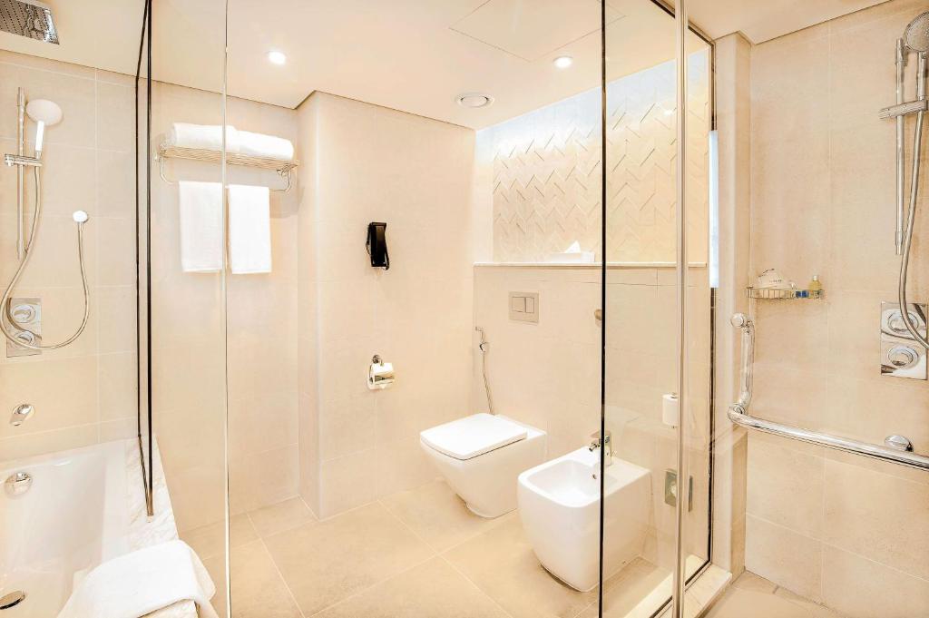 a bathroom with a toilet and a glass shower at Radisson Blu Hotel & Resort, Abu Dhabi Corniche in Abu Dhabi