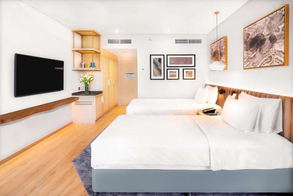 a hotel room with two beds and a flat screen tv at Radisson Blu Hotel & Resort, Abu Dhabi Corniche in Abu Dhabi