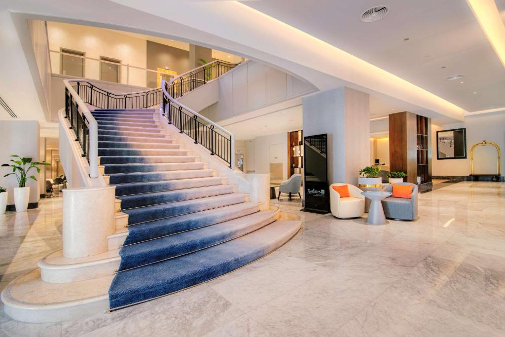 a spiral staircase in a lobby with orange chairs at Radisson Blu Hotel & Resort, Abu Dhabi Corniche in Abu Dhabi