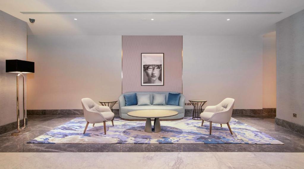 a living room with a blue couch and two chairs at Radisson Blu Hotel & Resort, Abu Dhabi Corniche in Abu Dhabi