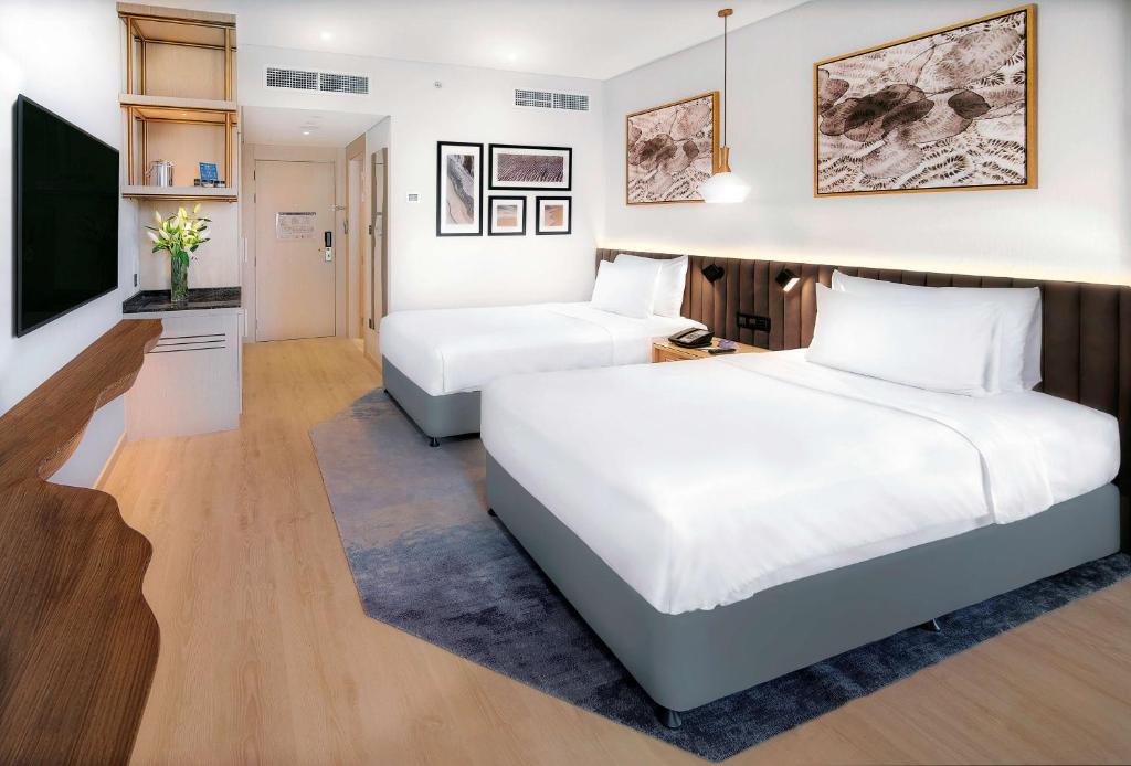 a hotel room with two beds and a flat screen tv at Radisson Blu Hotel & Resort, Abu Dhabi Corniche in Abu Dhabi
